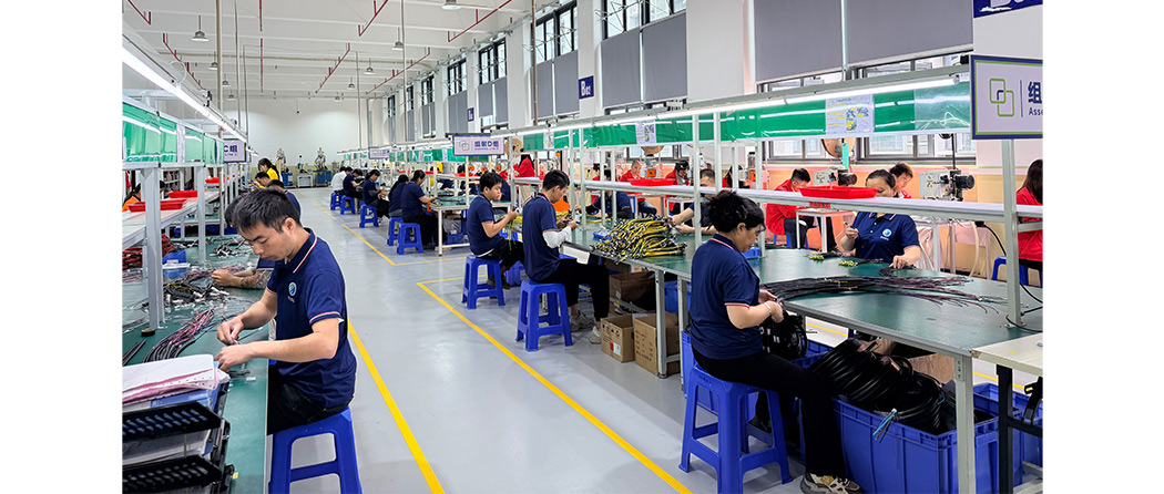 Skilled technicians performing wire harness assembly on workstations with pre-cut wires, terminals, and connectors.